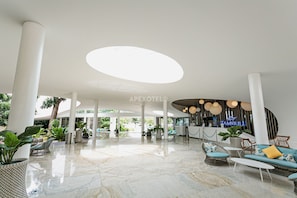Experience the warm welcome of our lobby, featuring a spacious seating area, reception desk, and lush greenery.