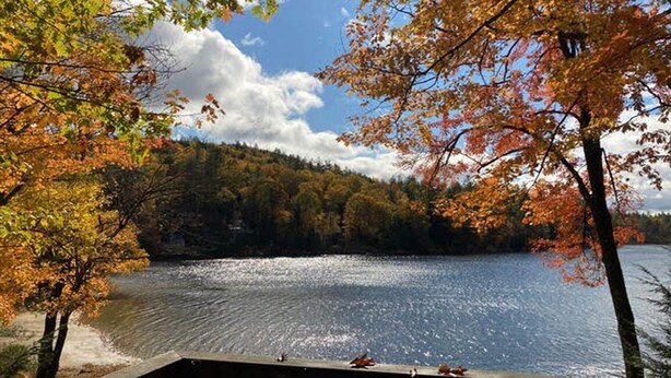 A lake with autumn foliage and a wooden deck. - Cozy Cabin on Loon Lake (Plymouth)
