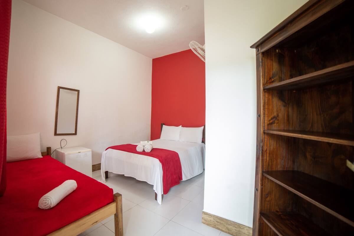 Ein Hotelzimmer mit zwei Betten, einem Holzschrank, einem Nachttisch und einer roten Wand.