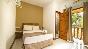 A bedroom with a bed, a nightstand, a window with curtains, and a view of greenery outside. - Pousada Cantinho do Sossego em Paraty (Paraty)