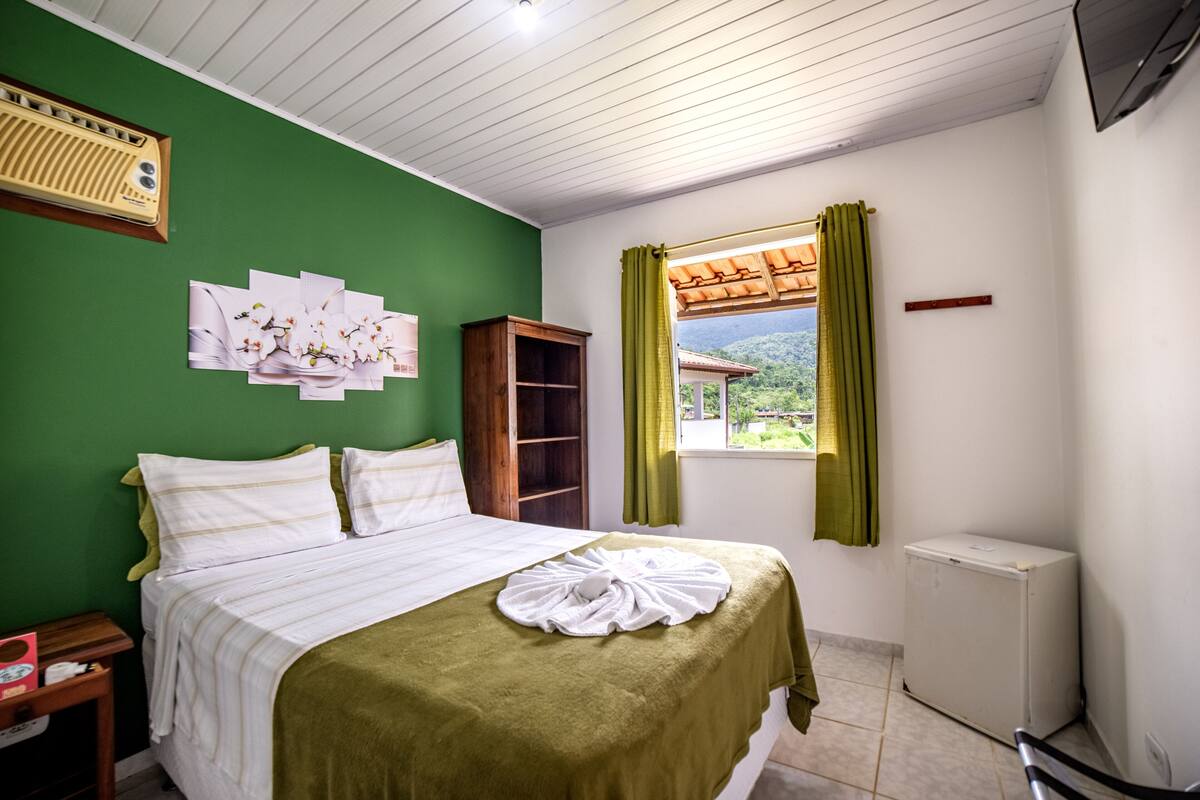 Ein Schlafzimmer mit Bett, Heizkörper, einem fensterbepflanzten Fenster und einer grünen Wand.