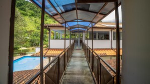 A covered walkway leading to a pool area with a sign reading "REFEITÓRIO". - Pousada Cantinho do Sossego em Paraty (Paraty)