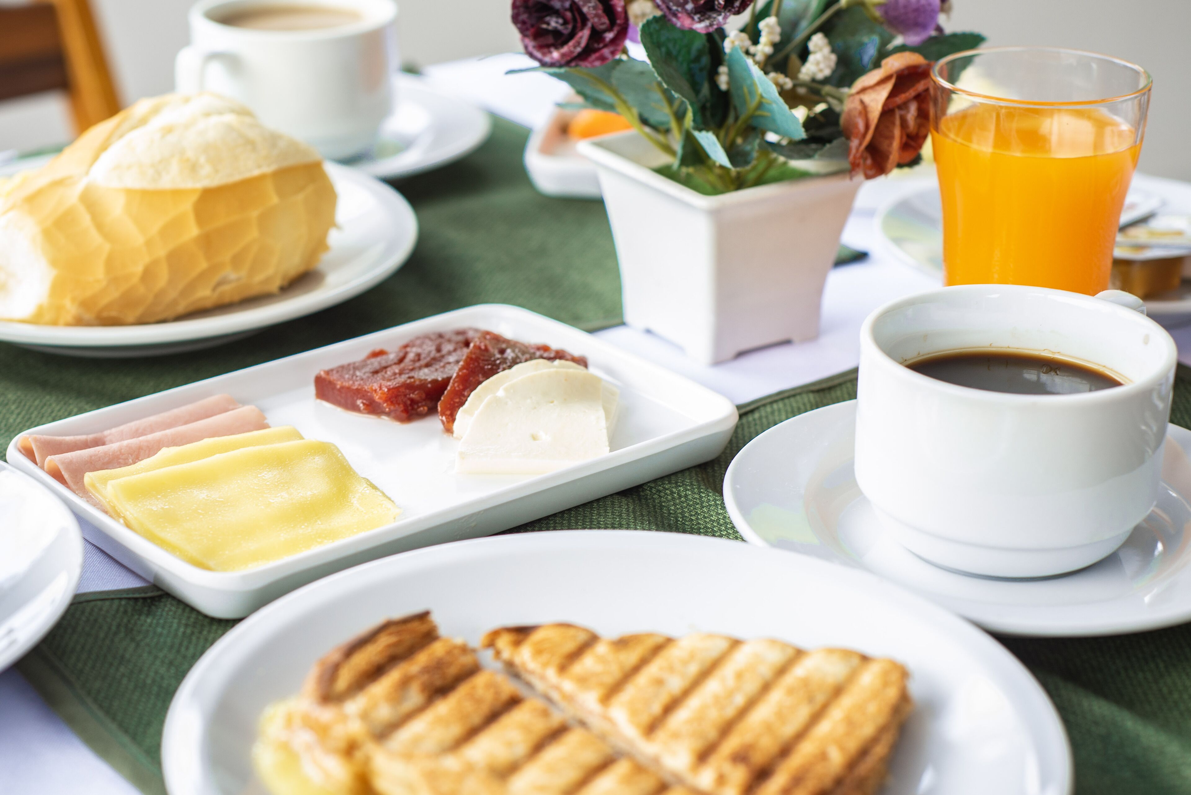 Une table dressée pour le petit-déjeuner, avec des assiettes remplies de nourriture, une tasse de café et un verre de jus d’orange.
