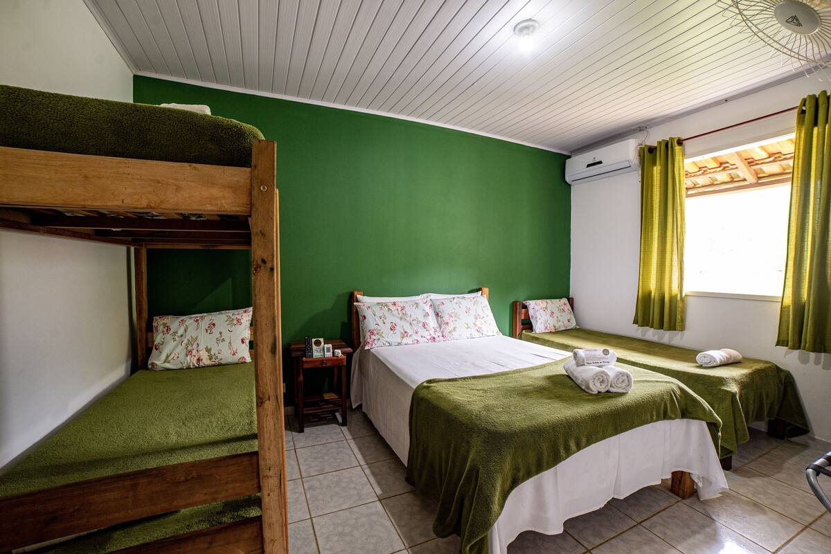 Ein Zimmer mit Etagenbetten, einem Einzelbett und einem Vorhangfenster.