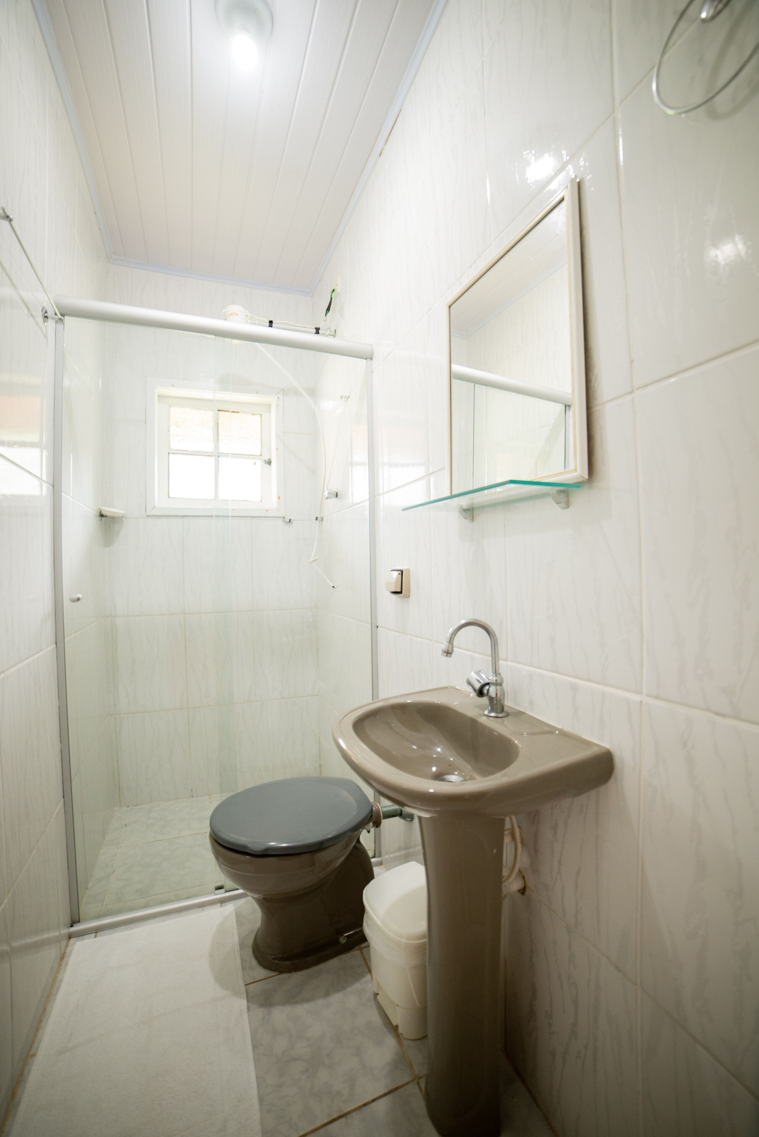 A bathroom with a toilet, sink, and glass shower enclosure.