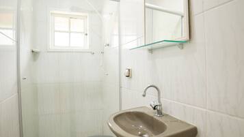 A bathroom with a toilet, sink, and glass shower enclosure.