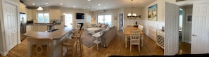 A spacious kitchen with a central island, a dining area with a wooden table and chairs, and a cozy living area with a sofa and chairs.