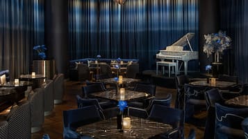 Un espace de restauration luxueux, agrémenté d’un magnifique piano à queue, de rideaux bleu foncé et d’un mobilier élégant.