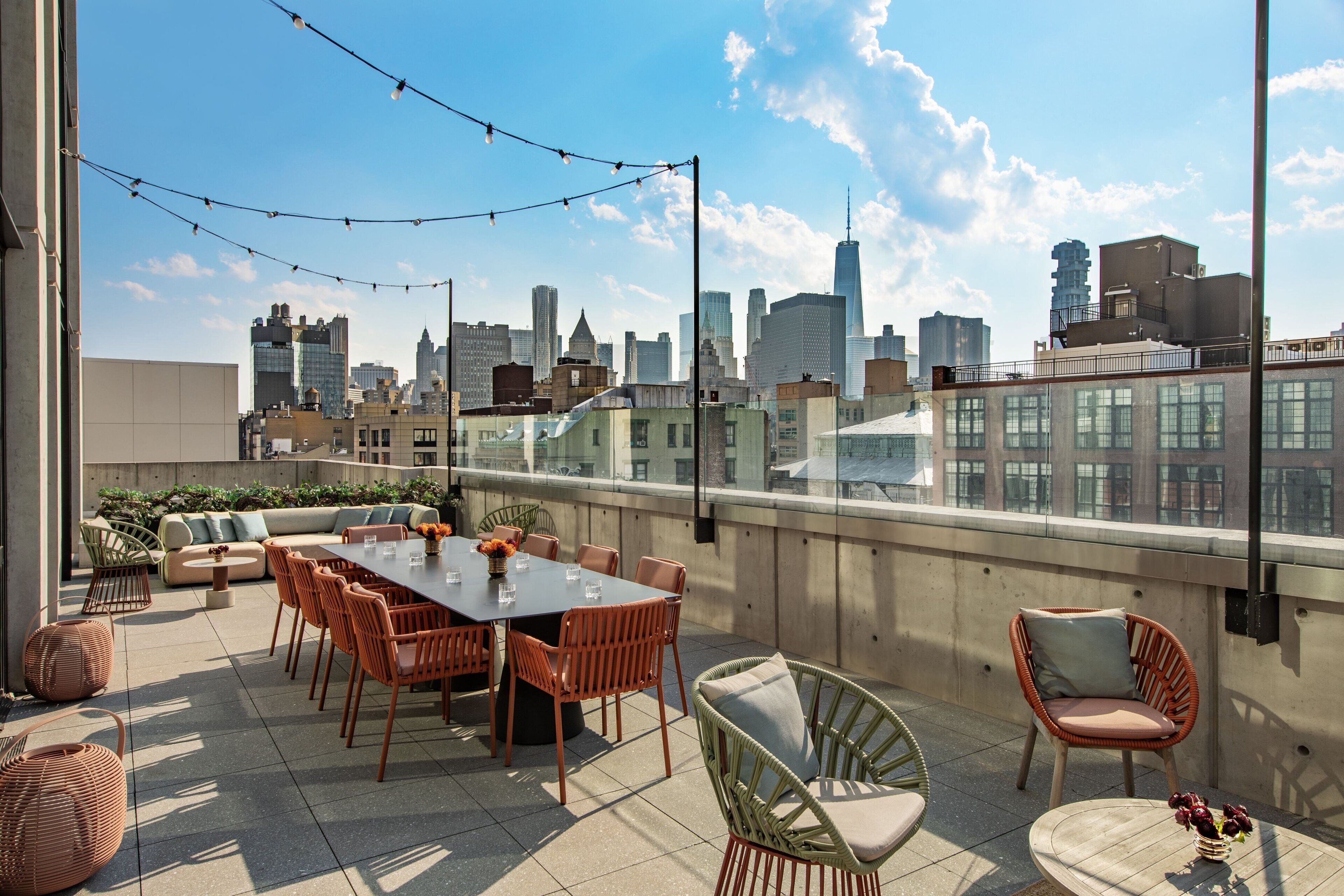 En tagterrasse med spiseplads, siddepladser og udsigt over byens skyline.
