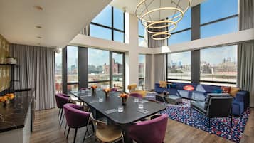 Una camera d'albergo moderna con angolo ristoro, divano e ampie finestre con vista sulla città.
