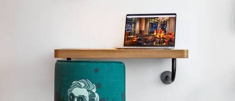 A laptop on a wooden shelf above a teal chair with a graphic design.