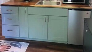 A kitchen with teal cabinets, a stainless steel sink, a microwave, and a coffee maker. - Modern studio with hot tub and patio access  (Poulsbo)