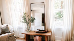 Una habitación acogedora con un banco de madera, un espejo, un florero con plantas y una cesta de mimbre.
