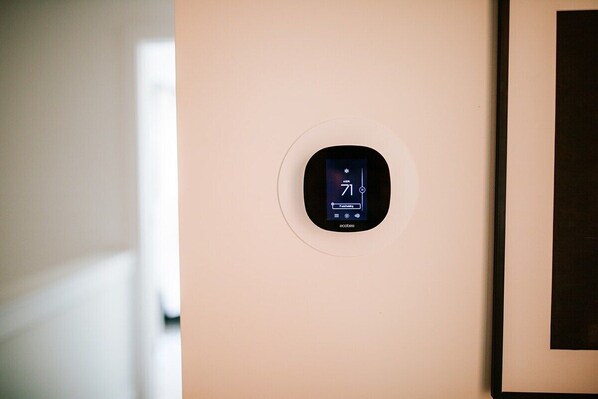 Un thermostat fixé au mur affiche une température de 71 degrés.