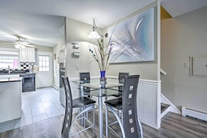 A modern kitchen with a glass dining table, black chairs, and a large abstract painting on the wall. - Family-Friendly Keansburg Home: Walk to Beach! (Keansburg)