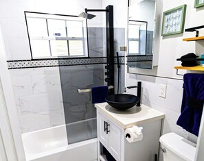 Un baño moderno con bañera, lavabo de color negro, toallero y retrete.