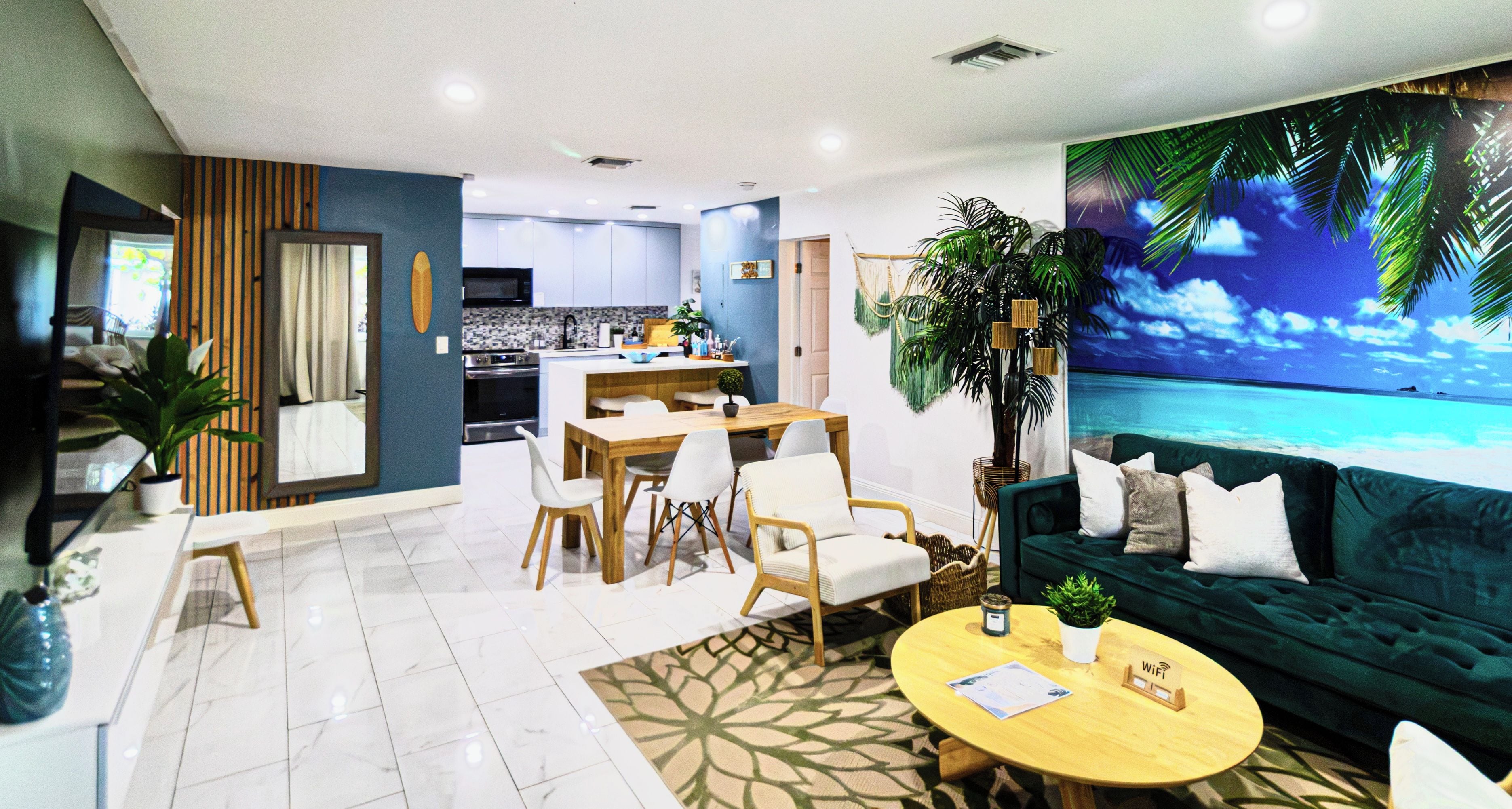 A modern living room with a green sofa, a wooden coffee table, and a dining area with a kitchen in the background.