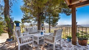 A wooden deck with a white table and chairs, surrounded by potted plants and a view of distant hills. - Cortijo La Alberquilla Íllora by Ruralidays (Granada)
