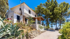 A two-story house with a balcony, surrounded by trees and a stone pathway leading to the entrance. - Cortijo La Alberquilla Íllora by Ruralidays (Granada)