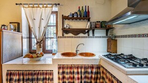 A kitchen with two sinks, a gas stove, and a window with a curtain. - Cortijo La Alberquilla Íllora by Ruralidays (Granada)