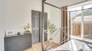 A bedroom with a metal bed frame, a grey dresser, a window with curtains, and a potted plant. - Charming Bend Home w/ Porch & Yard: Great Location (Bend)