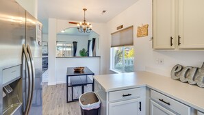 A modern kitchen with white cabinetry, a stainless steel refrigerator, a chandelier, and a window with a view of a fence. - Charming Bend Home w/ Porch & Yard: Great Location (Bend)