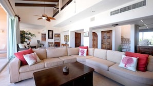A spacious living room with a large beige sectional sofa, a wooden coffee table, and a ceiling fan. - PRIME Location, Gorgeous Sweeping Views, PH right on the Beach, Villas del Mar 1 (Puerto Aventuras)