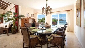 A dining area with a round table, wicker chairs, and a view of the ocean. - PRIME Location, Gorgeous Sweeping Views, PH right on the Beach, Villas del Mar 1 (Puerto Aventuras)