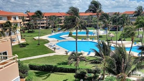 A resort with multiple swimming pools, palm trees, and a large building with a red roof. - PRIME Location, Gorgeous Sweeping Views, PH right on the Beach, Villas del Mar 1 (Puerto Aventuras)