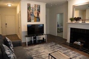 Cozy living space with a flat-screen TV, dark sofa, and wooden coffee table.