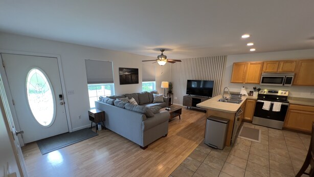 A modern living room with a grey sofa, a television, and a ceiling fan. - Relaxing 2 bedroom home minutes away from PMRP (Beattyville)