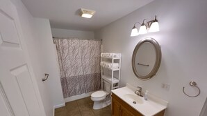 A bathroom with a toilet, sink, mirror, and shower curtain. - Relaxing 2 bedroom home minutes away from PMRP (Beattyville)