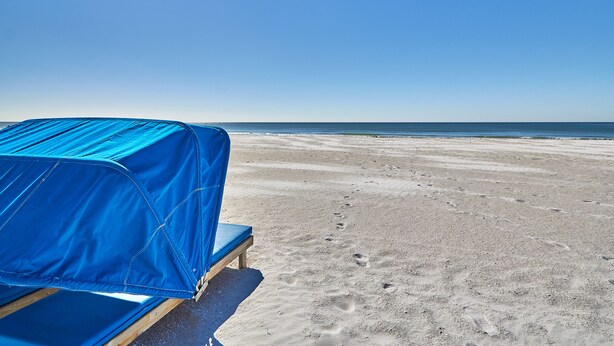 Ein Strand mit einem blauen Zelt und einer hölzernen Bank.