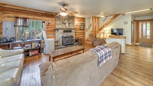A cozy cabin interior with a stone fireplace, wooden walls, a sofa, and a television. - Cozy Mountaintop Retreat < 6 Mi to Ski Cloudcroft! (Cloudcroft)