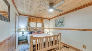 A bedroom with a wooden bed, a ceiling fan, a nightstand with a lamp, and a painting on the wall. - Cozy Mountaintop Retreat < 6 Mi to Ski Cloudcroft! (Cloudcroft)