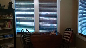 Un comedor con una mesa de madera, dos sillas y una estantería con libros y objetos decorativos.