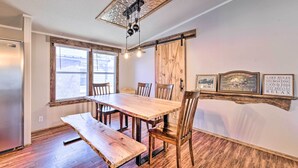 Ein Essbereich mit Holztisch und Bänken, einer Decke mit dekorativen Kacheln und einer Wand mit gerahmten Bildern.