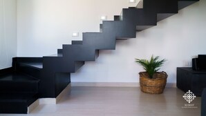 A modern staircase with black steps and white wall sconces. - Villa Vittoria  - Dimora fronte mare (Augusta)