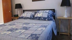A bedroom with a bed, two bedside tables, a door, and a framed picture on the wall. - Dragons Roost a cheerful 2 bedroom home in Toledo (Toledo)