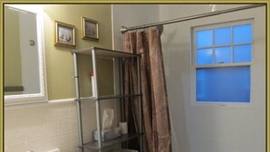 A bathroom with a white sink, a toilet, a shower with a curtain, and a window with blue-tinted glass. - Dragons Roost a cheerful 2 bedroom home in Toledo (Toledo)