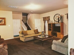 A living room with a beige sofa, a coffee table, a staircase, and a wooden cabinet. - Beautiful large home near Sea World,  Riverwalk, Fiesta Texas  (San Antonio)