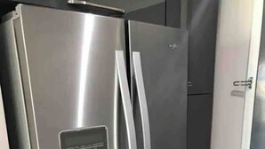 A stainless steel refrigerator with a water dispenser and a red towel hanging on the handle.