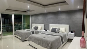 A modern bedroom with two beds, a balcony, and a nightstand with a phone.