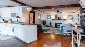 A spacious living area with a fireplace, a dining table, and a kitchen with white cabinets.