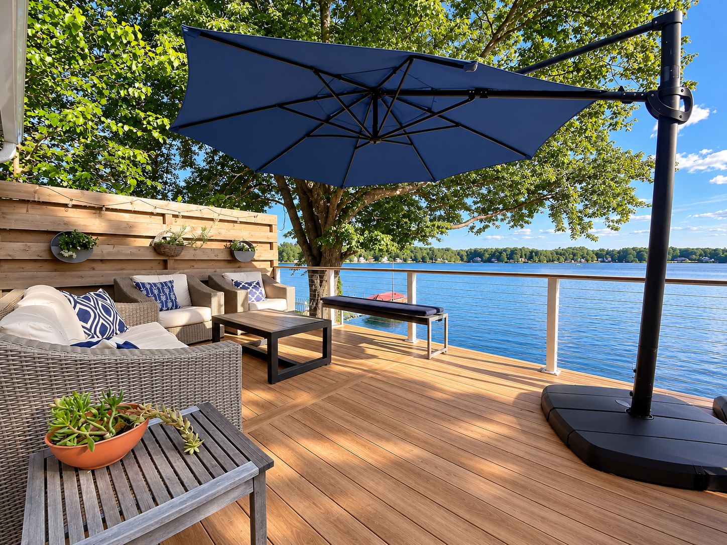 Une terrasse dotée de mobilier d’extérieur, d’un grand parasol et offrant une vue sur un lac.