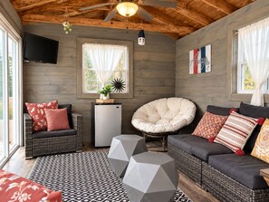 A cozy room with a wooden ceiling, a television, a refrigerator, a comfortable chair, a sofa, and a patterned rug. - Luxury Lakefront Retreat - Private Beach, Dock & Cozy She Shed (Sandown)