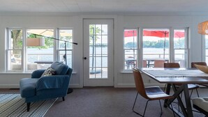A room with a large window, a dining table, and a blue armchair.