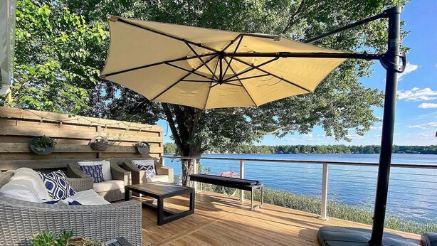 A wooden deck with wicker furniture, a swing, and a view of a lake.
