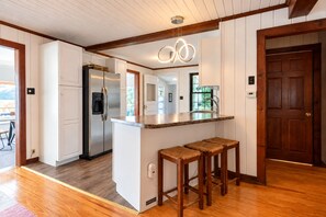 A modern kitchen with a central island, stainless steel appliances, and wooden stools.