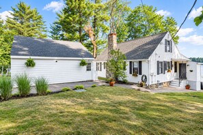 A two-story house with a stone chimney, a front porch, and a well-maintained lawn.